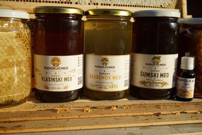 Tegle vlasinskog, bagremovog i šumskog meda sa etiketama, uz teglu saća i bočicu propolisa