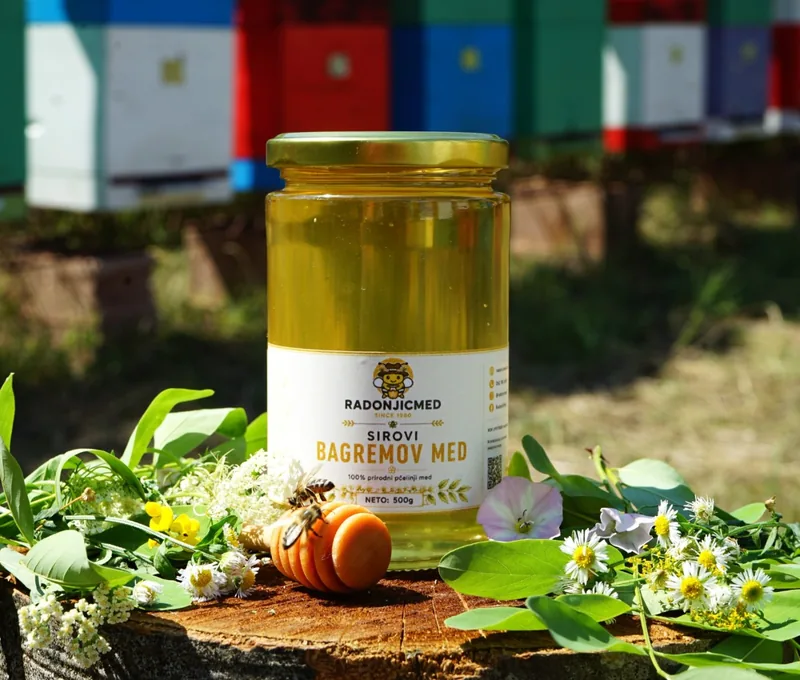 Tegla bagremovog meda od 500 g na panju, pčela na cvetu pored